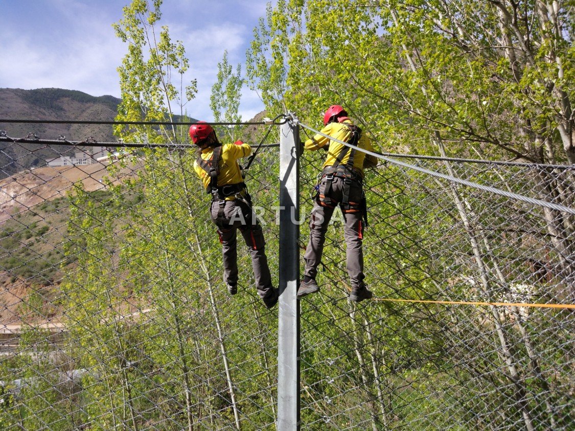 Two technicians connecting the barrier net to a post
